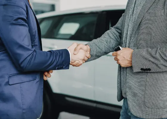 Auto loan handshake by a vehicle — auto note portfolios on Debexpert